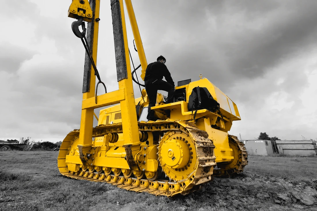 Sideboom in campo con il braccio alzato e un tecnico salito sul mezzo