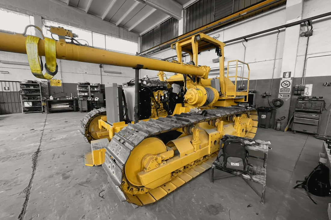 Sideboom CAT in officina con il motore scoperto e il braccio imbracato